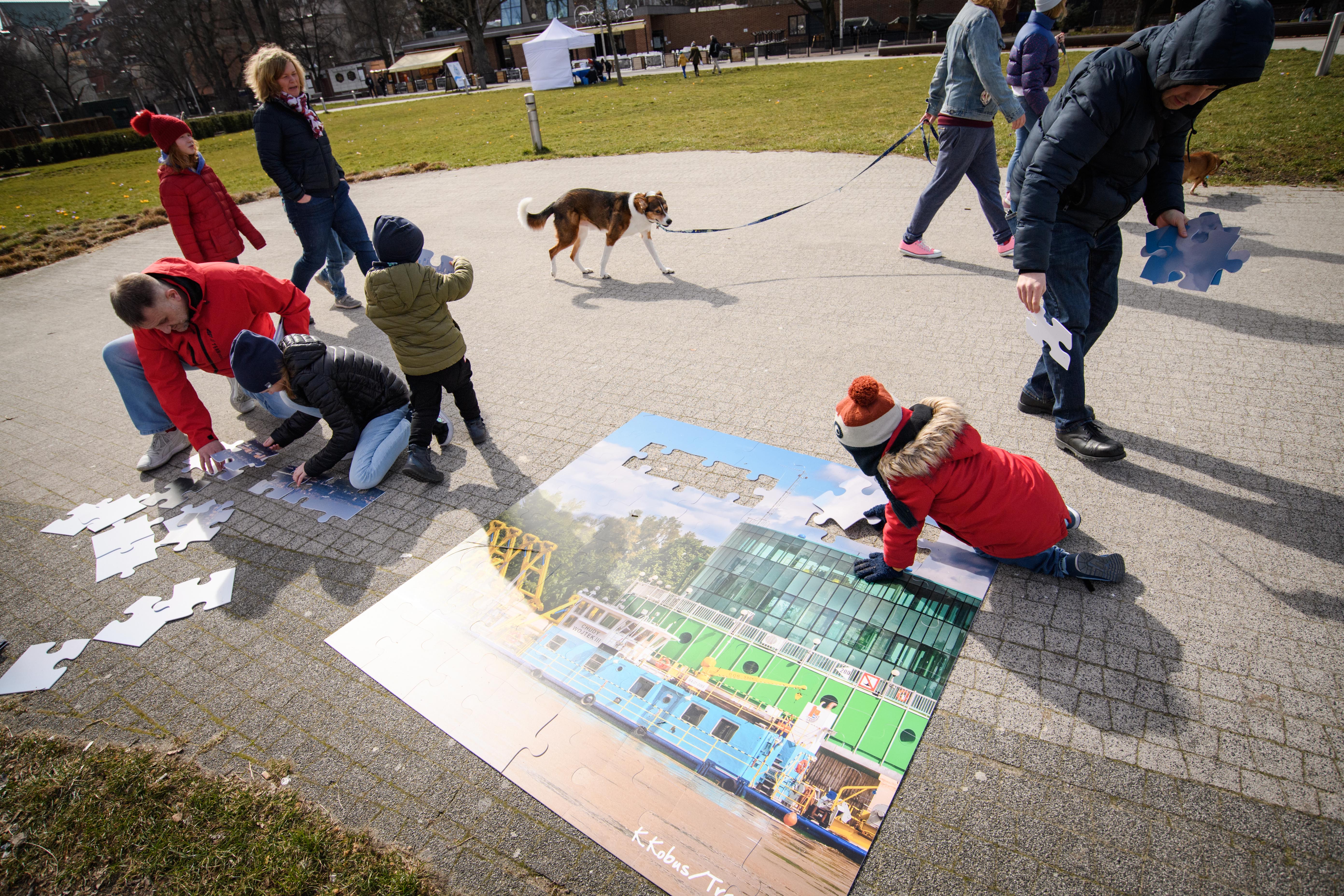 Dzieci i dorośli układający puzzle przedstawiające studnię infiltracyjną Gruba Kaśka