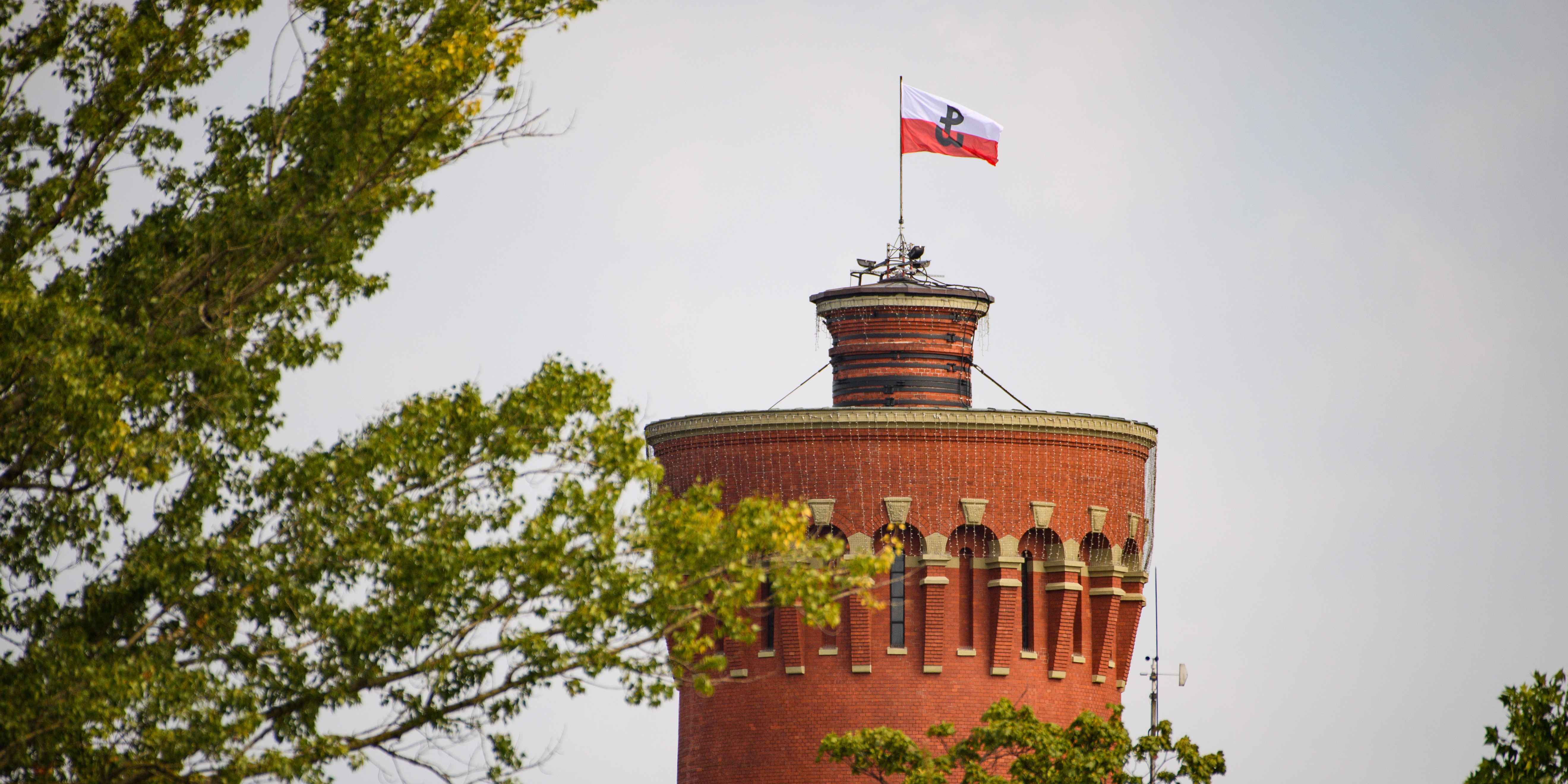 Flaga ze znakiem Polski Walczącej zatknięta na szczycie wieży ciśnień.